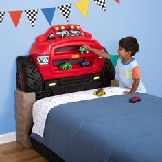 a little boy playing with his toy monster truck bed in his child's bedroom