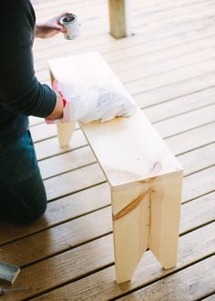 a person sitting on a wooden floor next to a table with a piece of wood sticking out of it