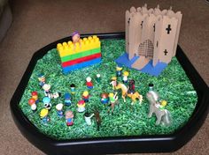 a table with toy figurines on it and a castle in the grass area