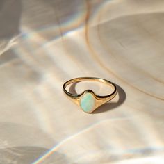 an opalite ring sitting on top of a white sheet with sunlight streaming through it