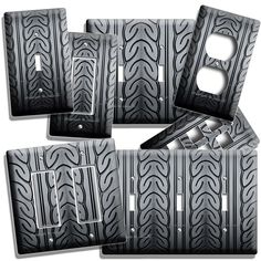 four black and white plates with silver designs on the front, one has a light switch plate