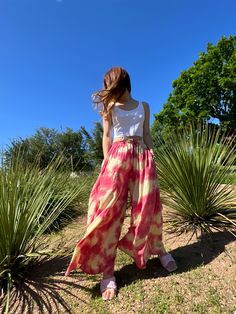 Step into a soft dreamscape of color with our Summer Tie-Dye Wide-Leg Pants. The perfect choice of vacation wear, these flared pants reflect free-spirited chic, letting you float through summer in unconfined comfort. Handcrafted from 100% Rayon, they offer exceptional breathability and a fluidic drape that keeps you cool and light as air all summer. It features an elasticated drawstring waist that offers an adjustable fit and side pockets for a practical flair. The vibrant tie-dye patterns captu Tie Dye Flare Pants Outfit, Bohemian Style Bottoms For Beach Season, Bohemian Bottoms For Beach Season Summer Outings, Summer Festival Wide-leg Harem Pants, Hippie Harem Pants For Vacation In Spring, Casual Pink Flare Wide Leg Pants, Casual Pink Wide Leg Flare Pants, Summer Vacation Wide-leg Harem Pants, Spring Flare Wide Leg Pants With Elastic Waistband