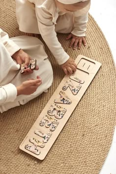 two children are playing with their cell phones on the floor in front of a wooden sign