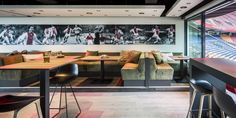 an empty sports bar with seating and pictures on the wall behind it in a stadium