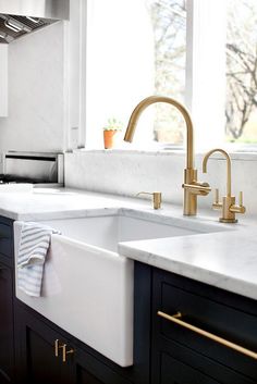 a kitchen with marble counter tops and brass faucets