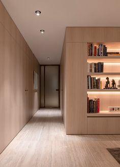 an empty hallway with bookshelves and lighting