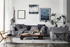 a living room with grey couches and pictures on the wall above them, along with a coffee table