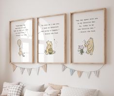 two winnie the pooh prints hanging on a wall above a couch with pillows and blankets