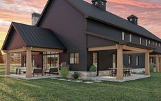 a large black house sitting on top of a lush green field