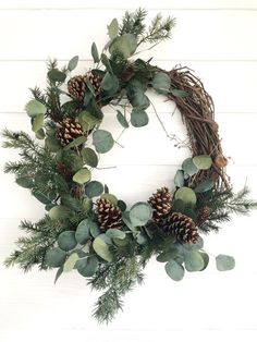 a wreath with pine cones and greenery is hung on the wall, ready to be used as a decoration