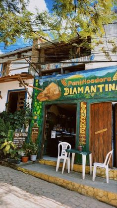 there are two white chairs outside of the restaurant with green and yellow lettering on it