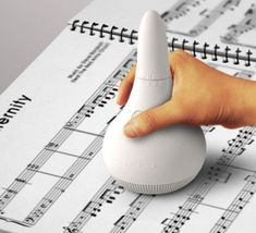 a hand pushing a white object on top of sheet music with the words read the music