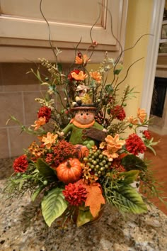 a vase filled with lots of flowers on top of a counter