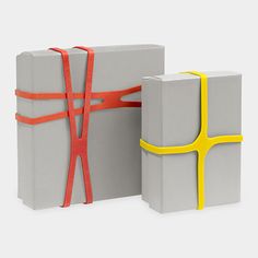 two gray boxes with yellow handles and one red ribbon tied around the edges are both wrapped in orange tape