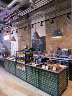 the inside of a restaurant with lots of food on display and lights hanging from the ceiling