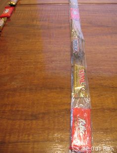 a candy bar wrapped in plastic sitting on top of a wooden table next to other candy bars