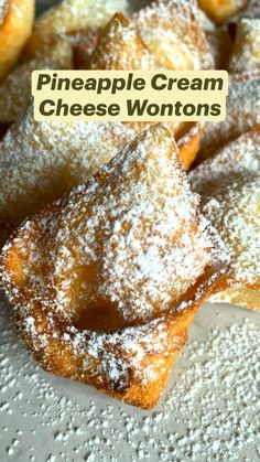 pineapple cream cheese wontons on a plate with powdered sugar over them