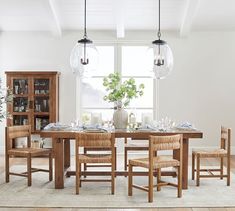 a dining room table and chairs in front of a window with an open bookcase