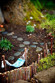 a miniature hammock in the middle of a garden with rocks and plants around it