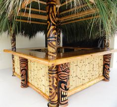 a tiki hut made out of bamboo and palm leaves with an icebox in the middle