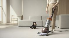 a woman with a vacuum and a dog on the floor