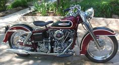 a red motorcycle parked on top of a sidewalk