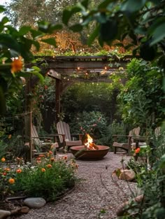 an outdoor fire pit surrounded by greenery and chairs with lights strung from the roof