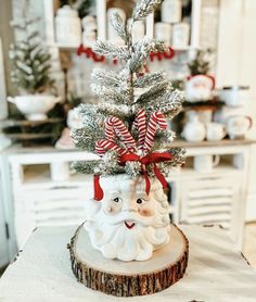 a small christmas tree decorated with candy canes and santa's head on a wood slice