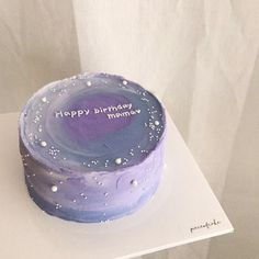 a purple and blue birthday cake sitting on top of a white table