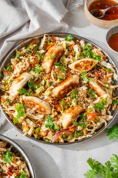 a bowl filled with chicken and vegetables next to two bowls of dipping sauces on the side