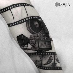 a man's arm with a film reel and camera on it, in black and white