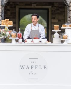 a man standing behind a counter filled with food