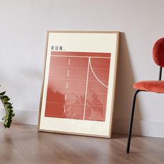 a red chair next to a framed poster on the wall with a basketball court in it