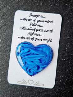 a blue heart shaped brooch sitting on top of a card