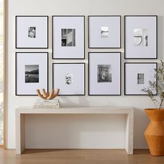 a white table sitting next to a wall with pictures on it