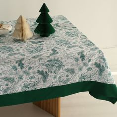 a table topped with a green and white christmas tree covered table cloth next to a seashell