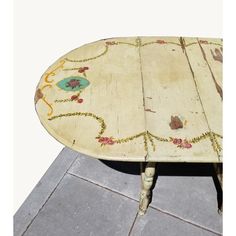 an old table has been painted with flowers and vines on it's top, while the rest of the table is made out of wood