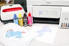 a printer and other supplies on a table next to a pillow, t - shirt