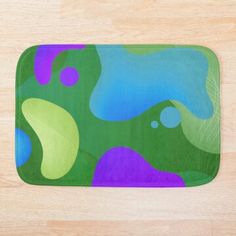 a green and purple bath mat sitting on top of a wooden floor