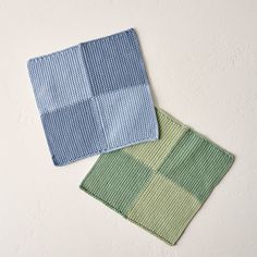 two blue and green dishcloths sitting next to each other on a white surface