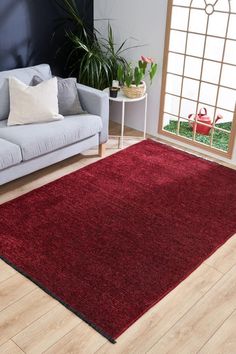 a living room area with a couch, chair and red rug on the hardwood floor