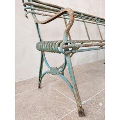 an old rusted metal bench sitting in front of a white wall with tile flooring