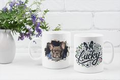 two coffee mugs sitting next to each other on a table with flowers in the background