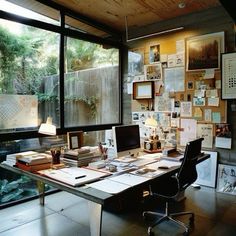 a home office with lots of pictures on the wall and desks in front of large windows