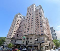 a large building with many windows on the top floor and cars parked in front of it