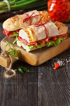 a sandwich with meat and cheese on a wooden cutting board - stock photo - images