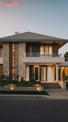 a modern house is lit up at night with lights on the front and side windows