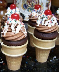 three ice cream cones with chocolate frosting and sprinkles, topped with cherries