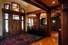 an entry way with wood paneling and wooden doors, rugs on the floor