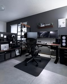 an office with two desks and several computer screens on the wall, along with shelves